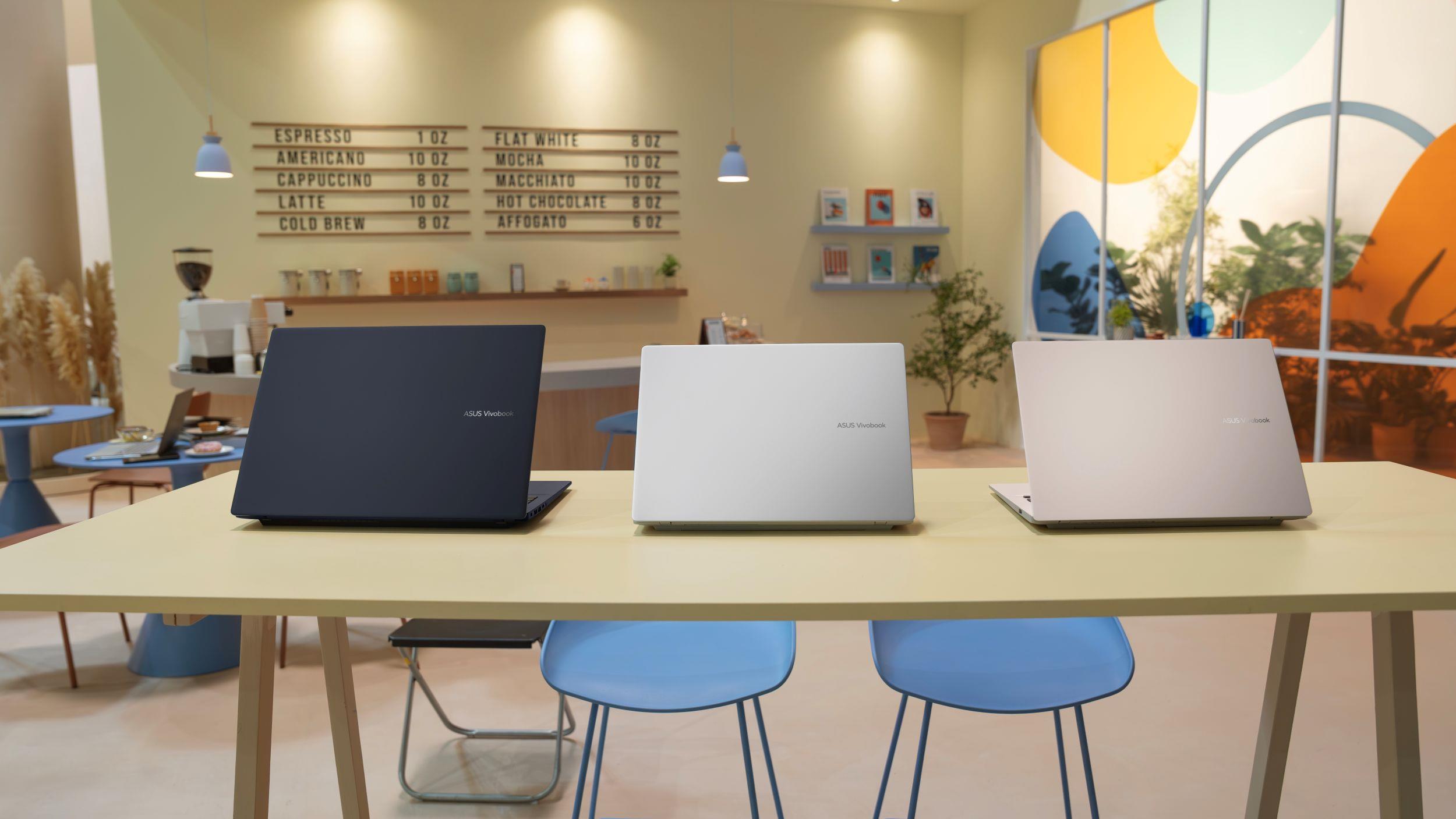 Three ASUS laptop arranged in a cafe environment open with their backs facing the camera.